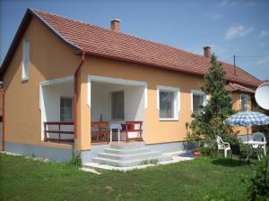 a yellow house with stairs and an umbrella at Abádi Karmazsin ház in Abádszalók