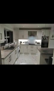 a large white kitchen with white cabinets and appliances at Cierons château in Derry Londonderry