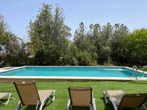una piscina con 2 sillas de césped y una piscina en Tramuntana home with swimming pool, Can Canonge, en Selva