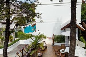 un patio al aire libre con piscina, mesas y sillas en Villa Sanpakoi en Chiang Mai