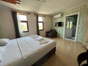 a bedroom with a white bed and a bathroom at Akar Butik Otel in Gokceada Town