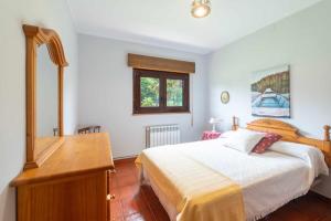 a bedroom with a bed and a dresser and a desk at Casa Vacacional Carmina in Quintana de Llanes