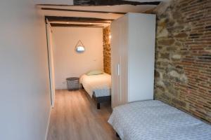 a bedroom with two beds and a brick wall at Les Remparts de Dinan . f3 intramuros. avec wifi in Dinan