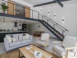 Una sala de estar con un sofá y sillas y una escalera. en Basswood Barn, en Wincanton