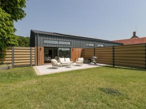 un patio trasero con 2 sillas y una casa en Basswood Barn, en Wincanton