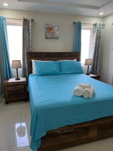 ein Schlafzimmer mit einem blauen Bett und Handtüchern darauf in der Unterkunft Bayfront Villa & Apartment in Portmore