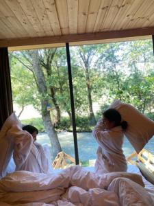 duas mulheres a dormir em camas num quarto com janelas em Lightwood cabins em Kʼareli