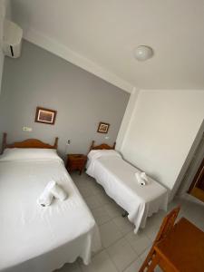 - 2 lits dans une chambre avec des draps blancs et des serviettes dans l'établissement Hostal Carlos III, à Aldea Quintana