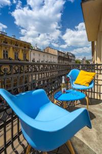 Kazimierz Friendhouse Apartments في كراكوف: زوج من الكراسي الزرقاء وطاولة على شرفة