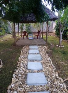 a walkway with two benches and a gazebo at Moringa Garden Cottage in Mtwapa