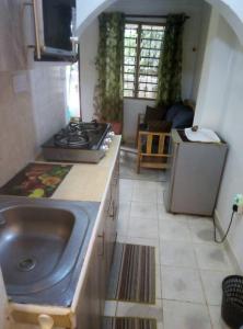 a kitchen with a sink and a stove at Moringa Garden Cottage in Mtwapa