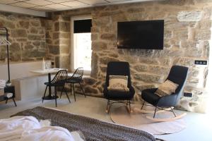 een kamer met stoelen en een tv aan een stenen muur bij Apartamentos Villa Maceira in Covelo