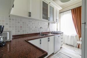 a kitchen with white cabinets and a sink and a window at Chic and Cozy Flat Near Istiklal Street in Beyoglu in Istanbul