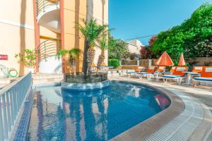 a swimming pool with chairs and a palm tree next to a building at Kos City Apartments in Kos