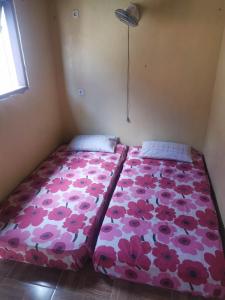 um quarto com uma cama com um padrão de flores cor-de-rosa em Villa panrangluhu em Bira