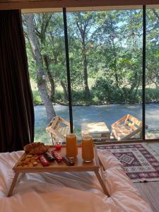 a bed with a table with two glasses of orange juice at Lightwood cabins in Kʼareli