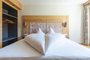 Schlafzimmer mit einem großen weißen Bett mit einem Kopfteil aus Holz in der Unterkunft hin&weg das Aparthotel in Ried im Zillertal