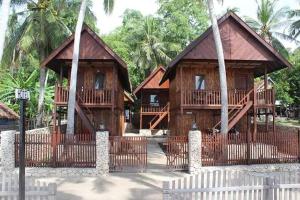 a couple of wooden buildings with palm trees at Villa panrangluhu in Bira