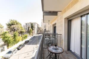 balcón con mesa y vistas a la calle en Shirat Haneviim - Isrentals, en Jerusalén