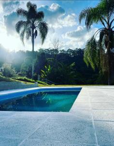 een zwembad met palmbomen op de achtergrond bij Recanto Vista Mantiqueira in Guararema