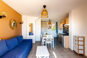 sala de estar con sofá azul y cocina en La Cabre d'Or - Duplex avec piscine partagée en Cabriès