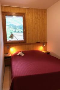 a bedroom with a red bed and a window at Les aiguilles d arves n 29 in Albiez-Montrond