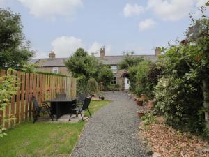 a garden with a table and chairs and a fence at Maple Tree Cottage in Morpeth