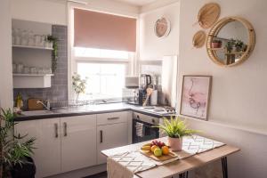 uma cozinha com armários brancos e uma mesa com frutas em Blackpool Abode - Laguna Studio Apartment em Blackpool
