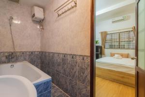 a bathroom with a tub and a bedroom with a bed at Kansas Hotel & Apartment - Notre Dame in Ho Chi Minh City