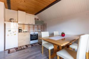 een keuken met een houten tafel en een witte koelkast bij Apartment and room Mateja Kovačič in Bohinj