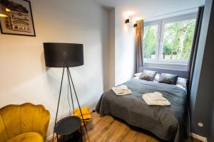 um quarto com uma cama, um candeeiro e uma janela em Apartament Verde em Toruń