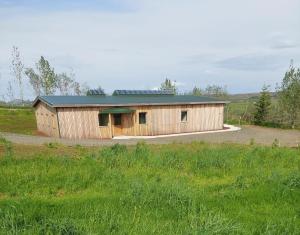 a wooden building with a green roof in a field at Klettar - The Old Hatchery Iceland in Fludir