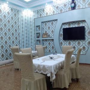 uma sala de jantar com mesa e cadeiras e uma televisão em UYUT INN Hotel em Samarcanda