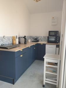 eine Küche mit blauen Schränken und einer Arbeitsplatte in der Unterkunft LE FAIERE AUDENGE in Audenge