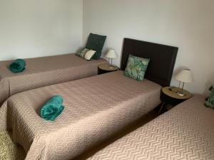 two beds in a room with two lamps on tables at casa da rochinha in Lajes do Pico