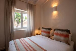 a bedroom with a bed with two pillows and a window at Nômade Melides Eco Lodge in Melides