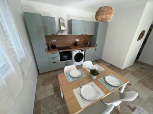 a kitchen with a wooden table and white chairs at La Bastide d’Elma - CLIM - WIFI in Sarrians