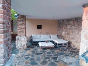 um pátio com um sofá, uma mesa e uma parede de tijolos em Garden House KRISTI em Kalandra