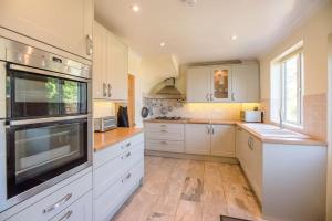uma cozinha com armários brancos e uma grande janela em Number 27, Alderton em Woodbridge