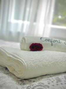 a white towel with a rose on top of it at Confort Apartament in Ploieşti