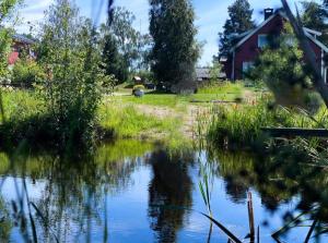 a view of a pond with a house in the background at Koselig hytte langs elven in Skien +3 photos
