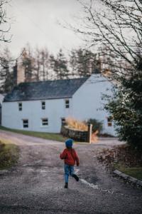 un jeune enfant marchant sur une route devant une maison dans l'établissement Exclusive use - The Coach House, à Banchory