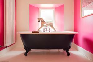 une baignoire noire dans une salle de bains rose dans l'établissement Exclusive use - The Coach House, à Banchory