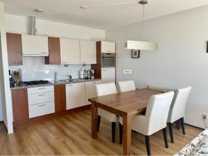 eine Küche mit einem Holztisch und weißen Schränken in der Unterkunft Duinerei appartement A101 in Groote Keeten