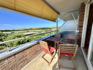 einen Balkon mit einem Holztisch und 2 Stühlen in der Unterkunft Duinerei appartement A101 in Groote Keeten