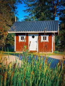 a small red and white house in the grass at Koselig hytte langs elven in Skien