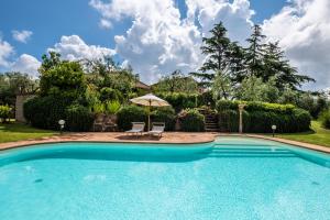 einen Pool mit 2 Stühlen und einem Sonnenschirm in der Unterkunft Cerchio Verde in Pitigliano