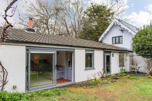 a white cottage with a large sliding glass door at The Secret Garden in Kingsdown