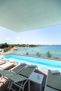 una piscina con sillas y el océano en el fondo en Dedaj Resort - Villa Tina en Zadar