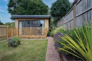 un piccolo capanno con una recinzione in legno in un cortile di The Garden Lodge - 1 Bedroom Lodge - Tenby a Tenby